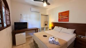 Un dormitorio con una cama con un televisor de pantalla plana. en Pousada Casa Centro Búzios, en Búzios