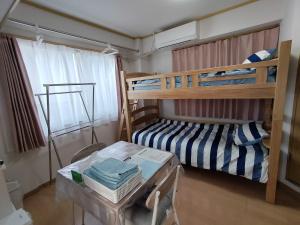 a bedroom with two bunk beds and a table at Guesthouse Mulberry Kagoshima- Vacation STAY 50746v in Kagoshima