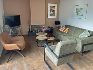 a living room with a couch and chairs and a television at Pet-Friendly Coastal Getaway in Breskens