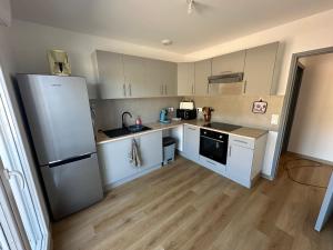 a kitchen with white cabinets and a refrigerator at Appartement climatisé in Château-Arnoux-Saint-Auban
