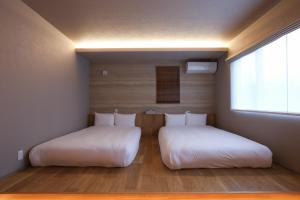 two beds with white sheets in a room with a window at Fuji Petel - Vacation STAY 56350v in Azagawa