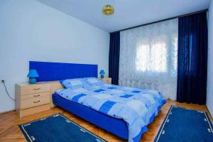 a bedroom with a blue bed and a window at Apartman Jelena in Soko Banja