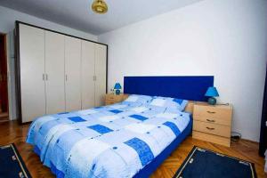 a bedroom with a blue and white bed and cabinets at Apartman Jelena in Soko Banja