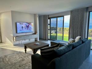 a living room with a blue couch and a tv at Casa de Santos - Bougain Villa in Mossel Bay