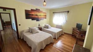 a hotel room with two beds and a television at VUT-Pico Aguasalio in Crémenes