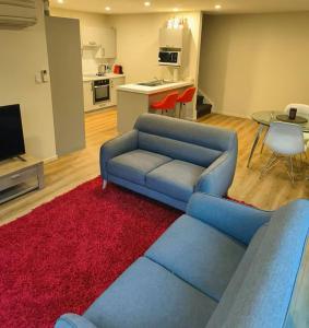 a living room with a blue couch and a red rug at City Town House in Christchurch