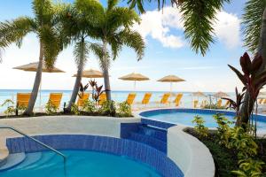 a swimming pool next to the beach with chairs and umbrellas at The House, An Autograph Collection All-Inclusive Resort - Adults Only in Saint James
