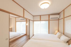 2 Betten in einem Schlafzimmer mit 2 Fenstern in der Unterkunft KINOTOMI - Vacation STAY 19643 in Ōtsu