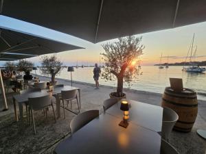 a restaurant with tables and chairs with a view of the water at Apartmani Rita Kiwi in Novigrad Istria