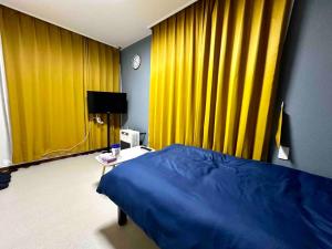 a bedroom with yellow curtains and a bed and a table at Coop Sunlight - Vacation STAY 19687 in Sapporo