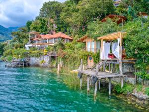 a dock with a bed in the water next to houses at Lake view paradise- waterfall, swim dock, kitchen in San Marcos La Laguna