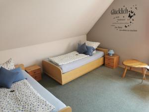 a small bedroom with two beds and a chair at Ferienwohnung Kerstin in Strackholt Ostfriesland- Urlaub in Großefehn 