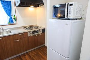 a kitchen with a white refrigerator and a microwave at Prosper No, 40 - Vacation STAY 19720 in Nagoya