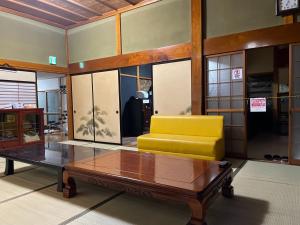 a living room with a yellow couch and a coffee table at Kominka Mimi - Vacation STAY 19741 