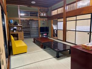 a living room with a table and a yellow chair at Kominka Mimi - Vacation STAY 19741 