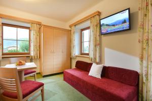 a living room with a red couch and a flat screen tv at Schneeberghof in Westendorf