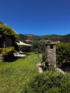 a garden with a bench and a stone house at La Casa negli Ulivi - con vista Mare in Arnasco