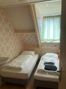 ウェスト・テルスヘリングにあるHuisje Stockholm op Terschellingの窓のある小さな部屋にベッドが2つある