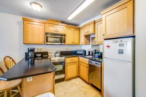 a kitchen with wooden cabinets and a white refrigerator at Beachy View at Rock Creek Inn in Rockaway Beach +20 photos