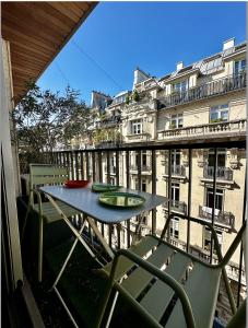 a table and chairs on a balcony with a view of a building at Stylish studio 3-4p with AC and balcony near Champs-Élysées in Paris