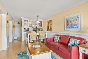 a living room with a red couch and a kitchen at A Place At The Beach 158 in Atlantic Beach