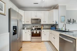 a kitchen with white cabinets and a stainless steel refrigerator at Marsh Winds 2K in Folly Beach