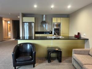 a kitchen with a counter and a chair and a sink at Littoral Living in Tauranga