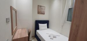 a small white room with a bed and a mirror at A few minutes from Siggrou Street in Athens