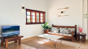 a living room with a couch and a tv at Pousada Ubatuba Villa Tupi in Ubatuba