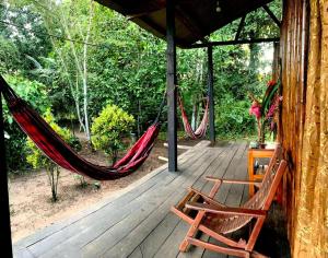 a porch with two chairs and a hammock on it at Oropendola Expeditions in Tambopata