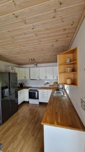 a kitchen with white cabinets and a wooden ceiling at Seaside cabin with stunning view! in Ålesund