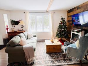 a living room with a christmas tree and a couch at Chalet -Havre au bord de l'eau in Chertsey