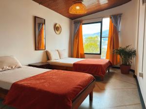 une chambre d'hôtel avec deux lits et une fenêtre dans l'établissement La Chiva Hostal Armenia, à Armenia