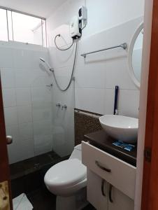 ein Badezimmer mit weißer Toilette und Waschbecken in der Unterkunft Departamento Frente al Cc Mega plaza - Ica in Ica