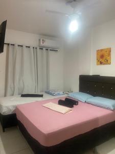 two beds in a room with a pink bedvisor at Apart - em frente á praia dos milionários- Ilhéus in Ilhéus +32 photos