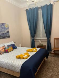 ミラノにあるApartment Suite Angelaのベッドルーム1室(青いカーテンと黄色の枕が備わるベッド1台付)