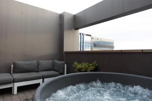 クライストチャーチにあるHuge Stylish Art Loft with Spa & Soaring Ceilingsのソファのある部屋の中央にバスタブがある