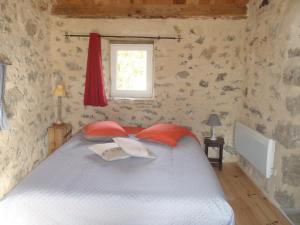 Schlafzimmer mit einem Bett mit roten Kissen und einem Fenster in der Unterkunft chambres du Domaine de Bombes in Mostuéjouls