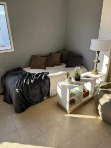 a bedroom with a bed with a black blanket and a table at Temporario Mitre in Vuelta del Paraguayo