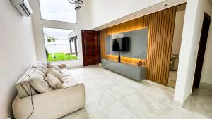a living room with a couch and a flat screen tv at Mansão Climatizada com piscina e churrasqueira in Camaçari