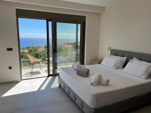 a bedroom with a bed with a view of the ocean at Thalassasense villa lourdata in Kefallonia +50 photos