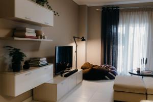 Una sala de estar con televisión y un sofá. en Apt D5, en Tesalónica