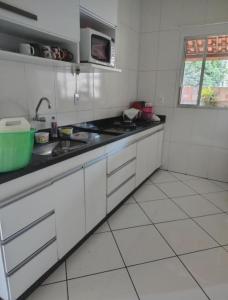 Una cocina blanca con fregadero y microondas. en Casa próxima ao expo Minas, en Belo Horizonte