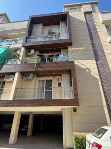 an apartment building with a balcony and a car at Chandigarh Waale, Furnished Stay in Zirakpur in Zirakpur