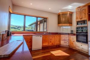 a kitchen with wooden cabinets and a large window at Karapiti Lodge - Stunning Rural Getaway in Horohoro +55 photos