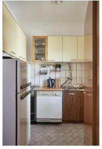 a kitchen with white appliances and brown cabinets at Peaceful apartment with yard and parking in Skopje