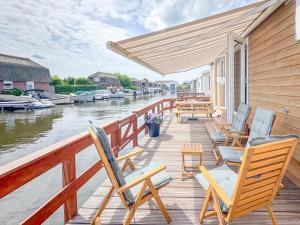 a wooden deck with chairs and tables on a river at Fuut 24-28 in Breukelen