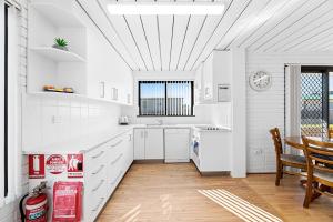 a kitchen with white cabinets and a table and a dining room at Apollo Unit 25 Ground Floor in Narooma