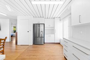 a kitchen with white cabinets and a stainless steel refrigerator at Apollo Unit 25 Ground Floor in Narooma