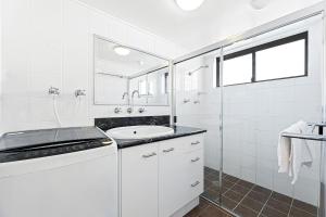 a white bathroom with a sink and a shower at Apollo Unit 25 Ground Floor in Narooma